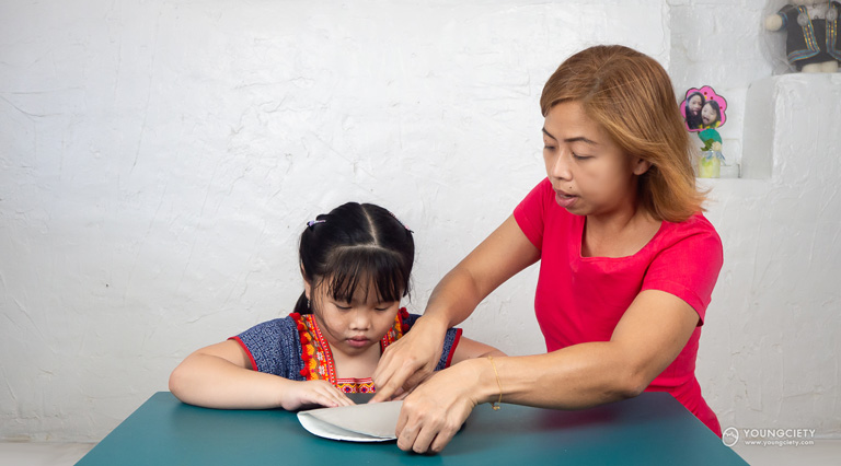เด็กและผู้ปกครองข่วยกันพับจานกระดาษ
