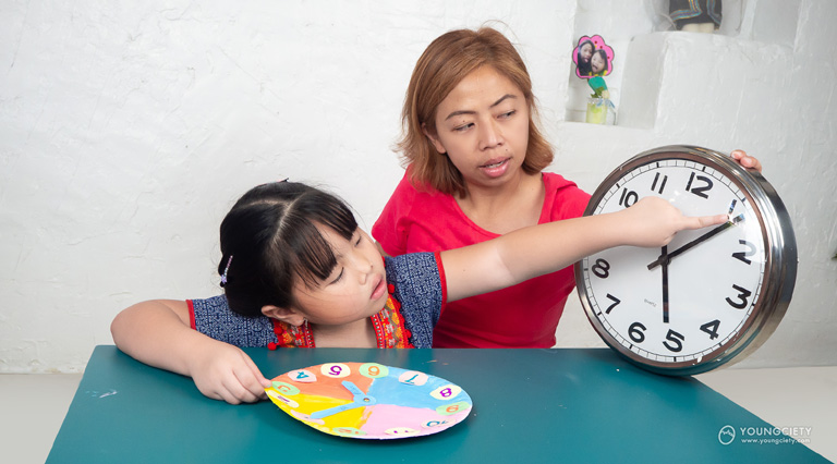 เด็กเปรียบเทียบนาฬิกาของจริงกับนาฬิกาที่ตนเองทำ