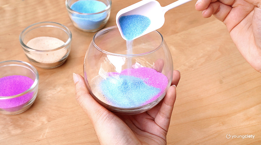 โรยทรายสีใส่ในแก้ว โดยสลับสีไปเรื่อย ๆ ให้เป็นชั้นสวย ๆ