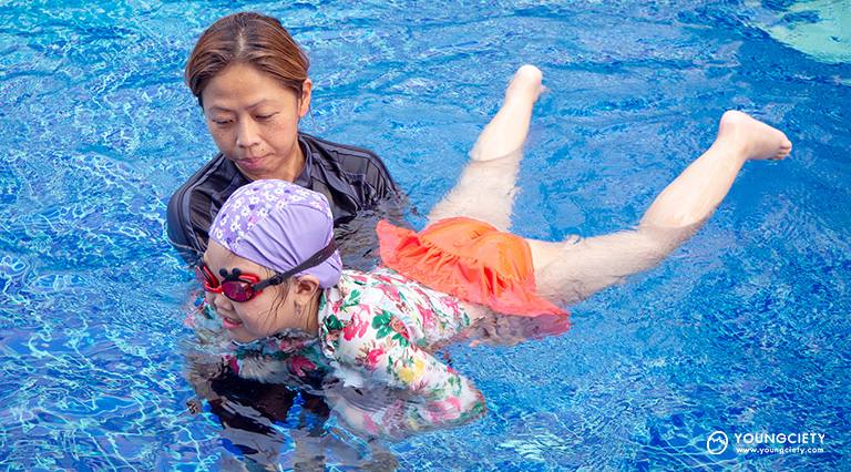 คุณแม่กำลังสอนลูกเตะขาในสระว่ายน้ำ